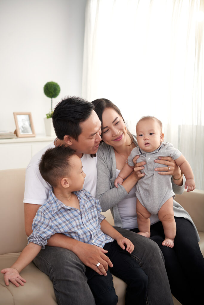 happy asian husband wife two kids sitting couch home